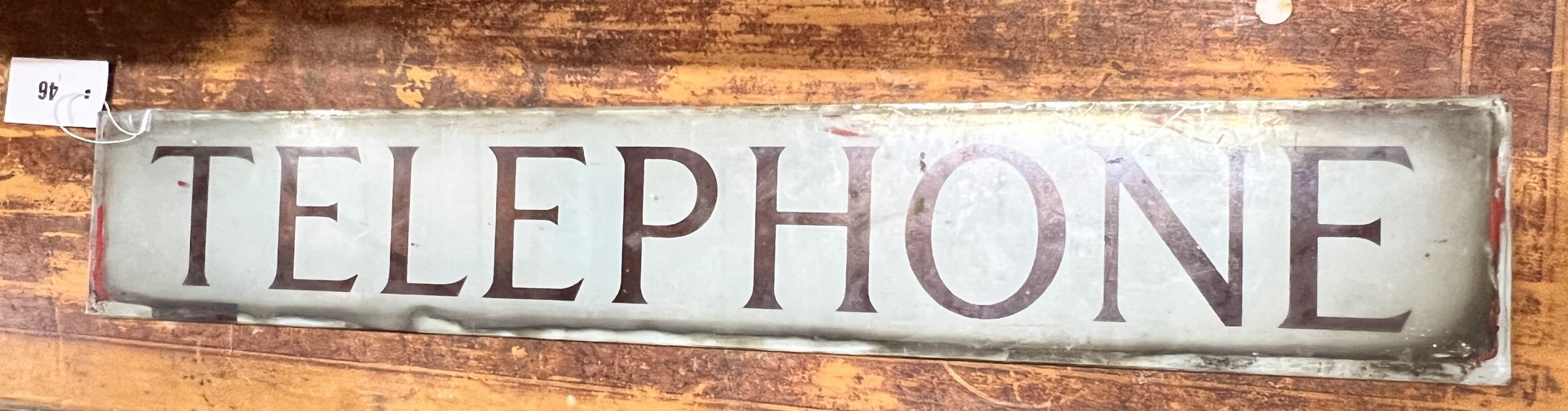 A vintage glass telephone box sign, width 64cm, height 10cm